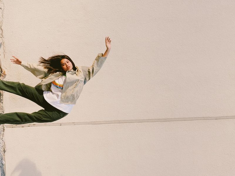Person in a fluid motion pose against a dark, minimalist background.